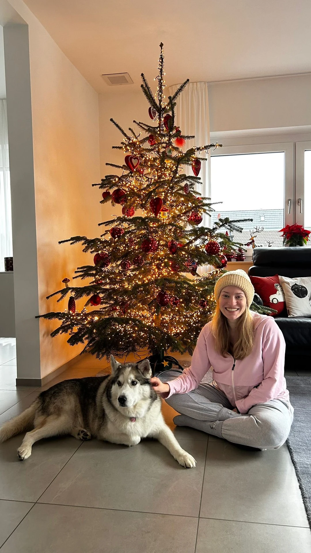 Mit einem Hund neben dem Weihnachtsbaum